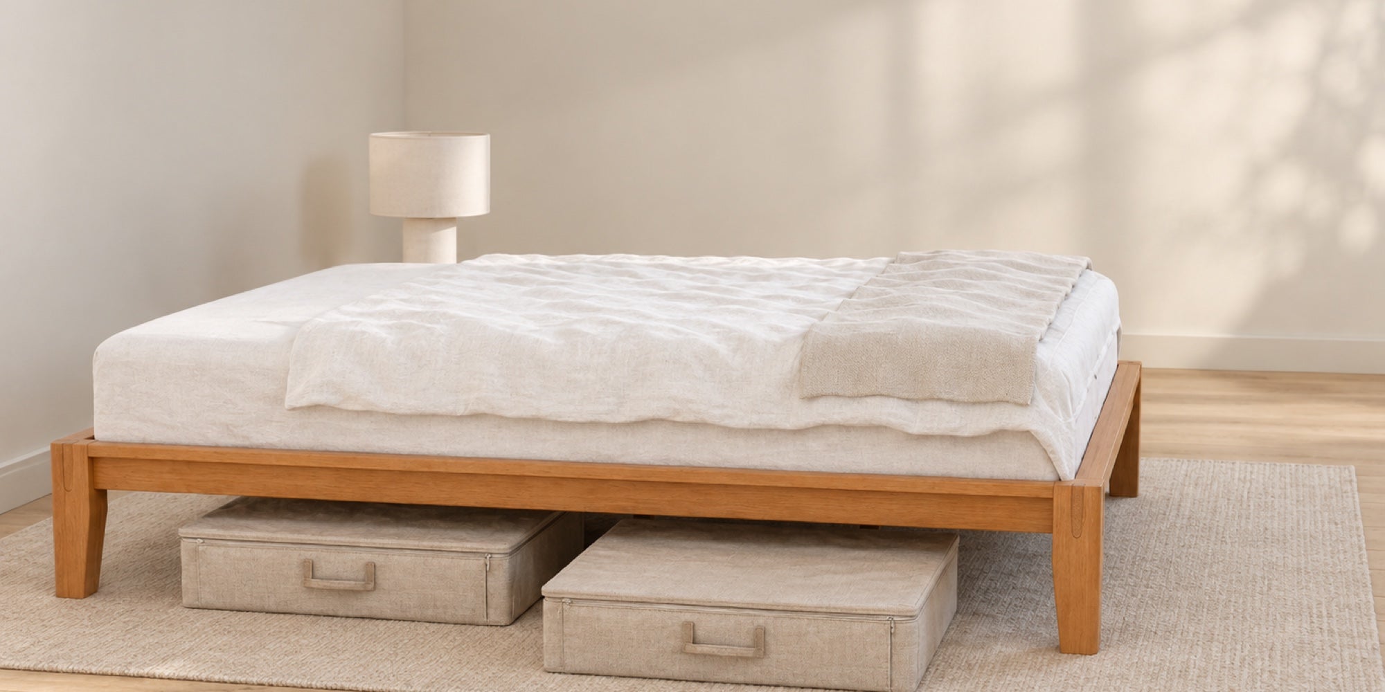 Angled long-side view of the Brintavo Queen Bed Frame with the rear leg visible and two separate low-profile fabric storage cases beneath the side rail